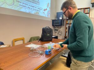 Il Lab Manager di PM_TEN Lorenzo Caponi mentre prepara il materiale per il seminario, strumenti appoggiati sulla cattedra dell'aula